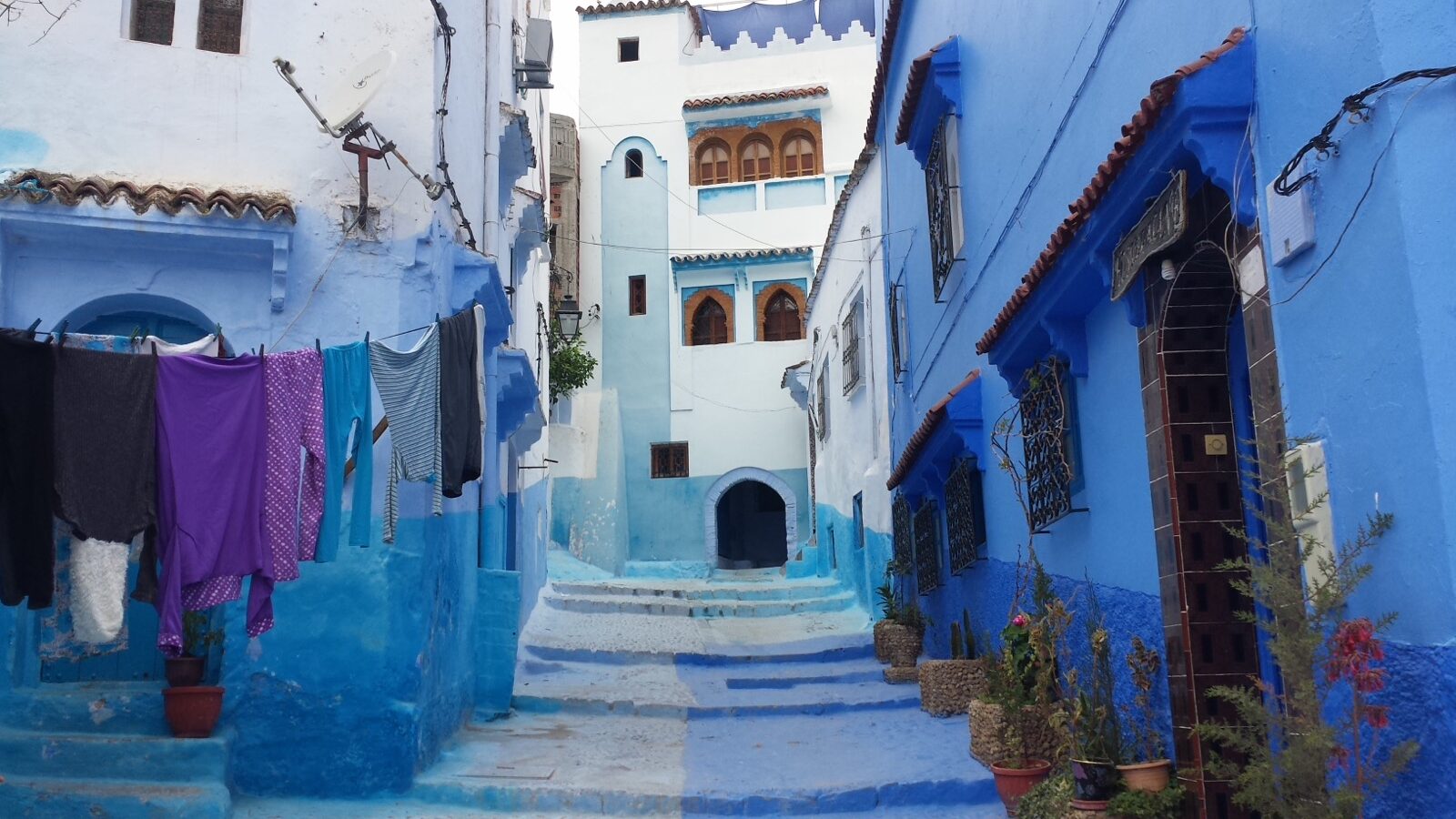 Traveller checking a phone map in a narrow blue lane in Chefchaouen