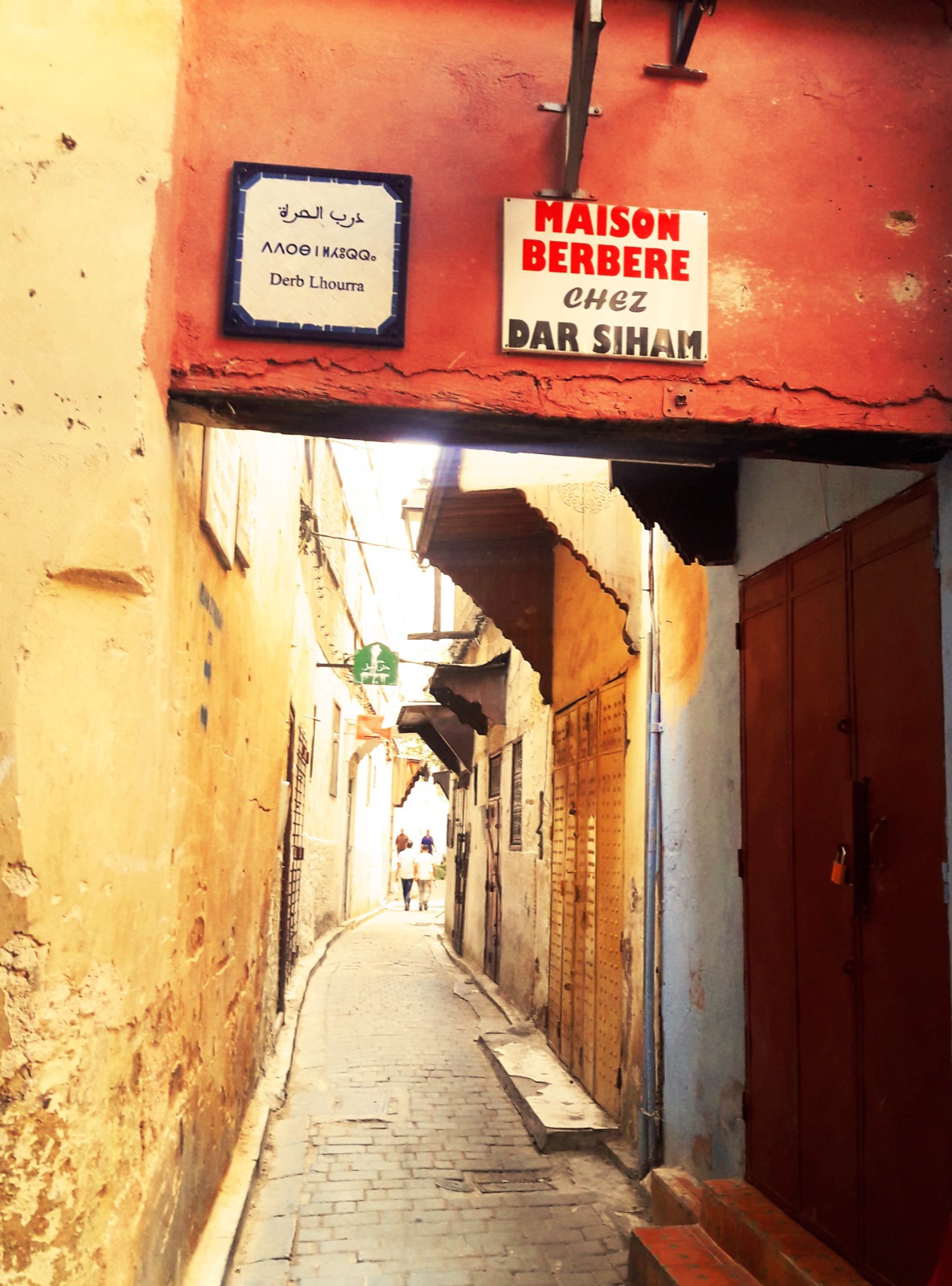 Hands holding a smartphone in a narrow alley of the Fes medina