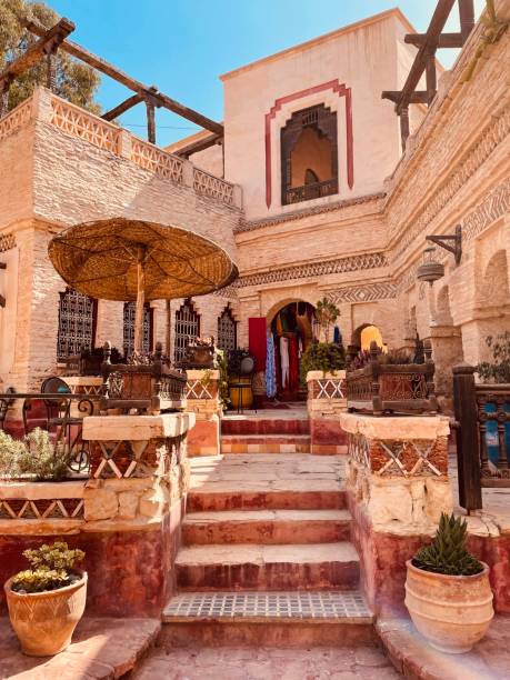 Sunlit tiled courtyard with carved cedar doors inside a historic riad in the Marrakech medina