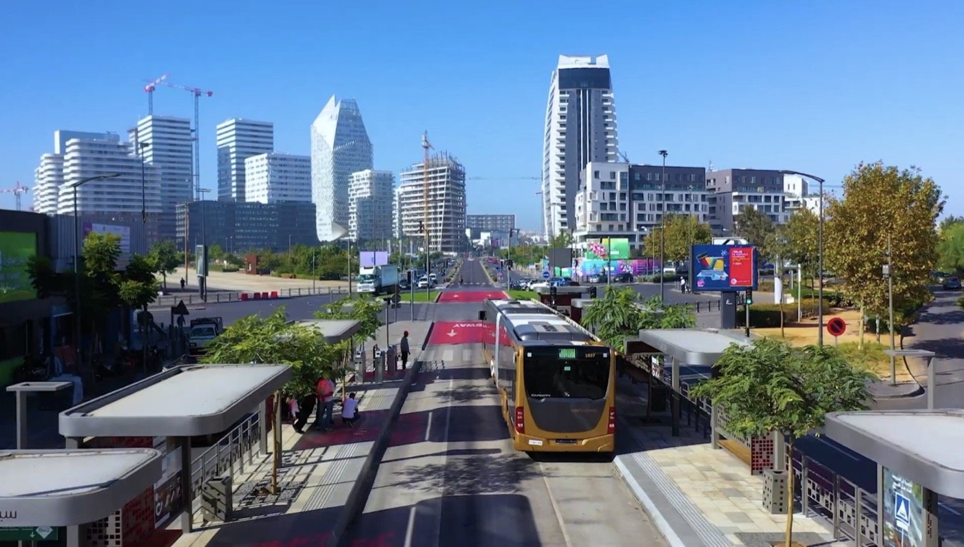 A red petit taxi and a Casablanca tram on a wide city boulevard