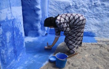 Solo traveller standing confidently with her phone on a blue street in Chefchaouen