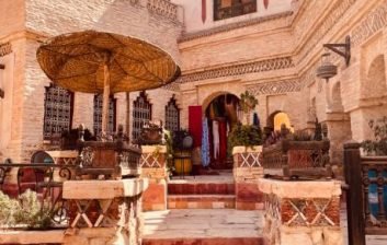 Sunlit tiled courtyard with carved cedar doors inside a historic riad in the Marrakech medina